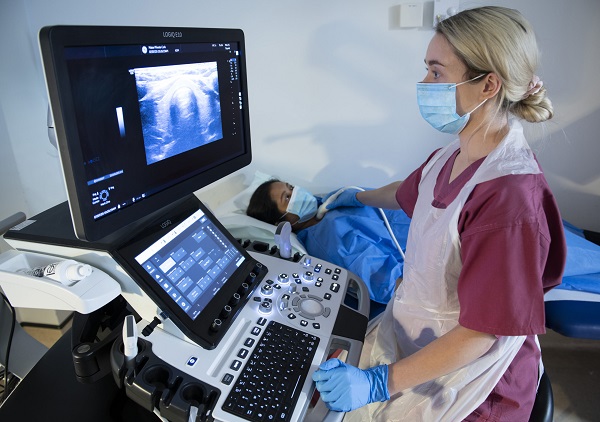 A Doctor taking scan while looking at the image in computer of a patient