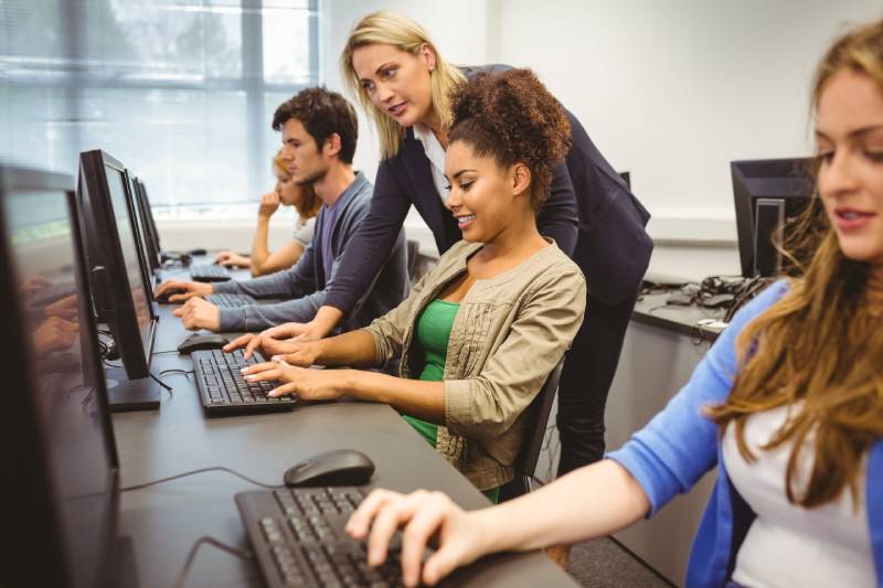 An instructor giving software education to a group of young businessminds in a training room.